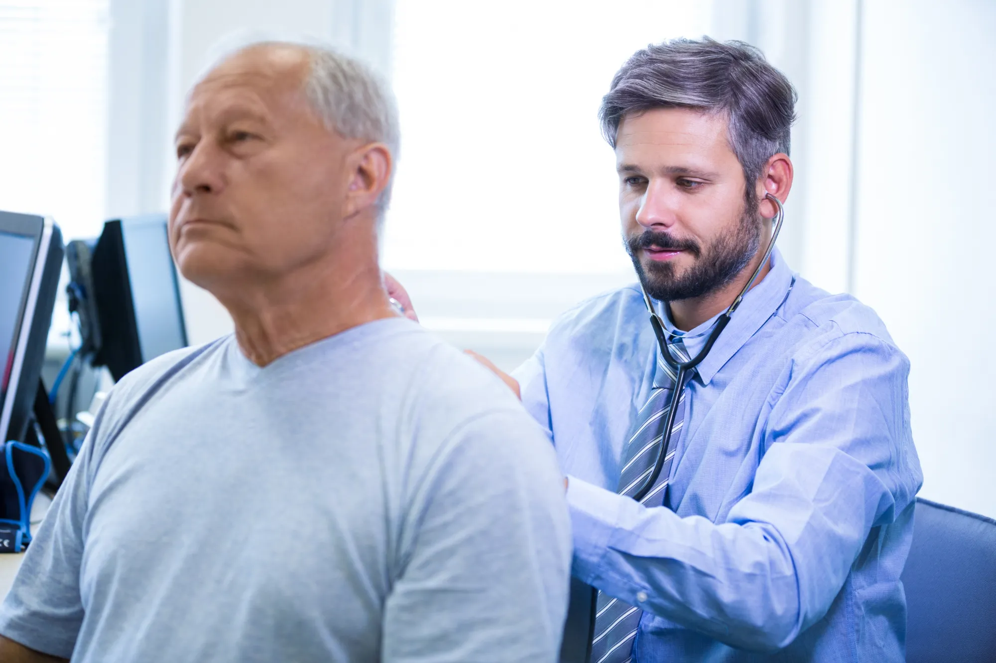 A doctor using a stethoscope to listen to an elderly man's pulse